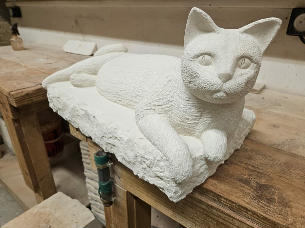 Sculpture en pierre "Tervoux" représentant un chat allongé sur un bloc dans un atelier