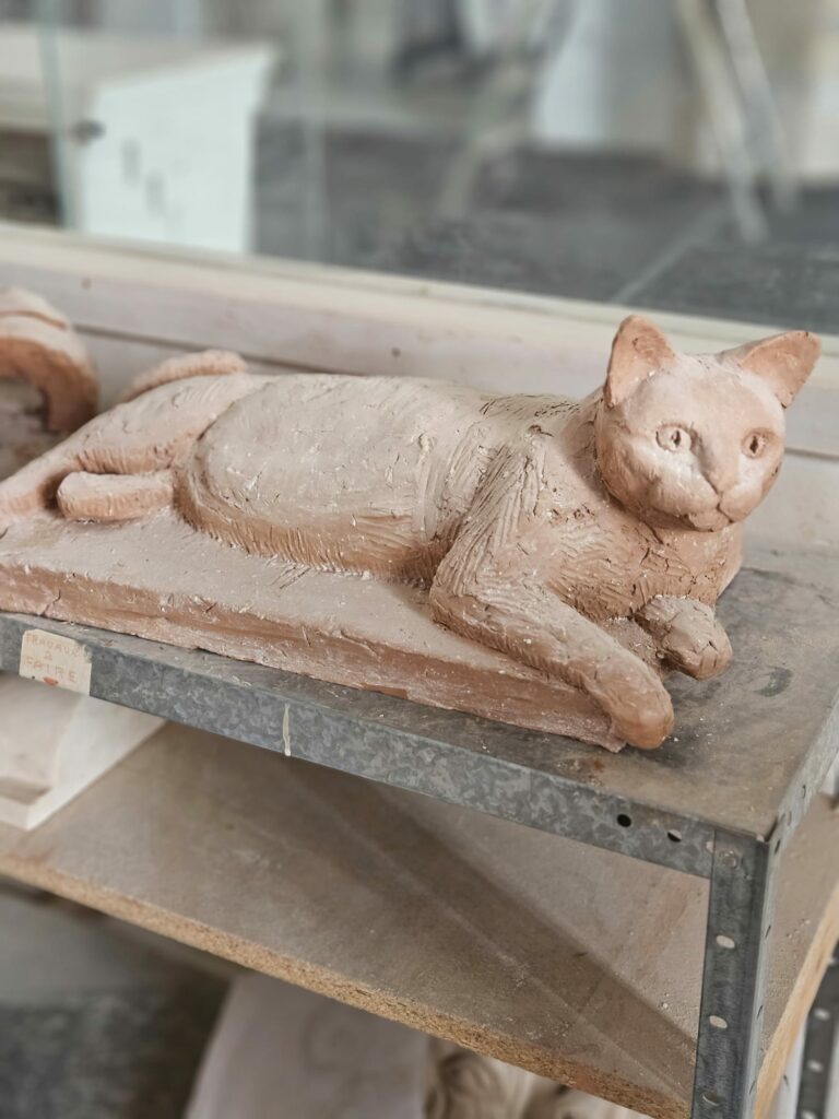 Sculpture en argile représentant un chat allongé sur un socle, en cours de modelage dans l'atelier de l'Académie des Arts d'Avignon.